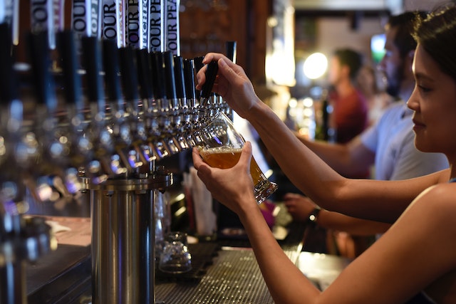 A bartender pours a pint of on-tap amber ale at a local craft brewery
