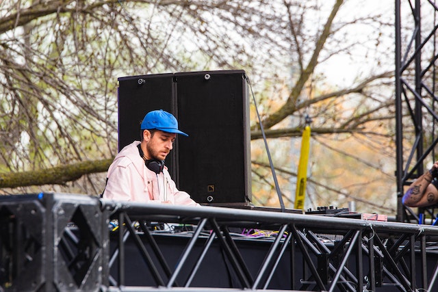 a deejay in a blue hat prepares for a set at the regina folk fest