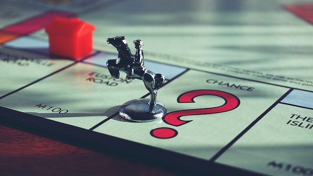 a game tocken shaped like a cowboy on a horse sits on the chance square on a monopoly board