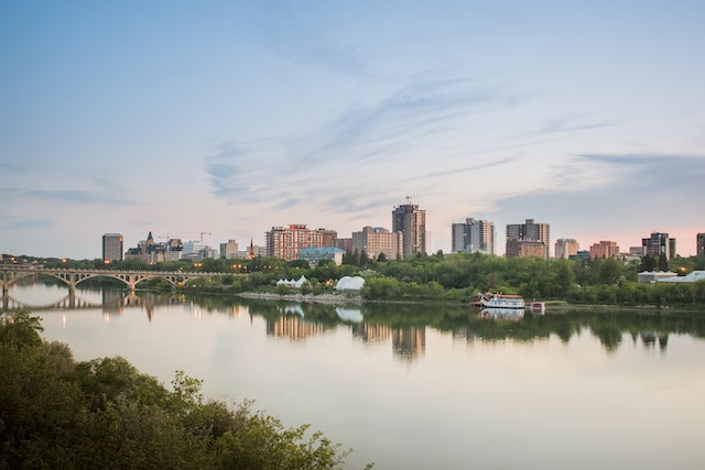 A west facing view of Saskatoons skyline in the early evening the south saskatchewan river is calm and reflects the skyline above