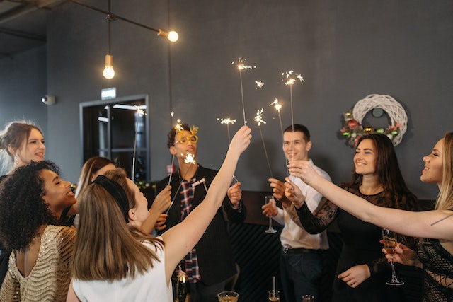 group of people at a holiday party holding sparklers and laughing
