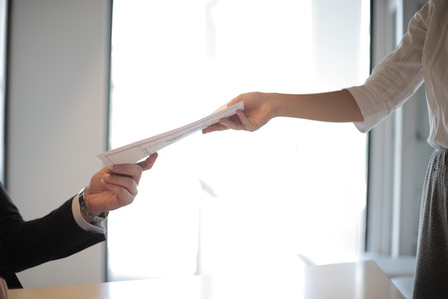 person passing a document to someone else across a table