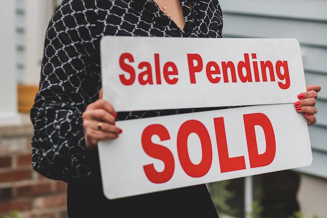 real estate agent holding a sale pending sign