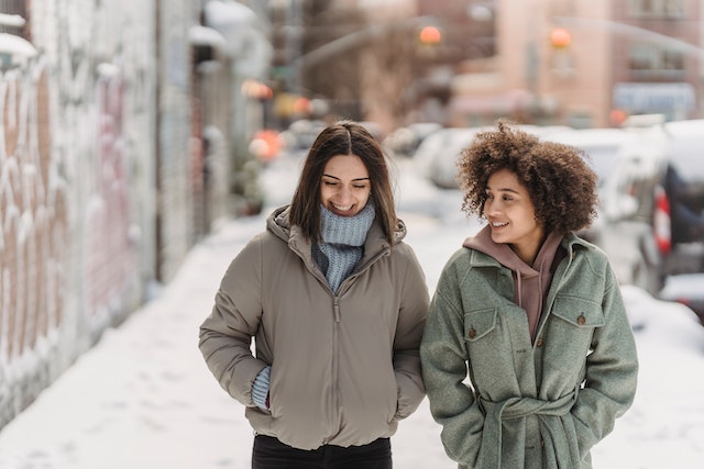 Two friends layer sweaters under winter jackets while walking in downtown saskatoon