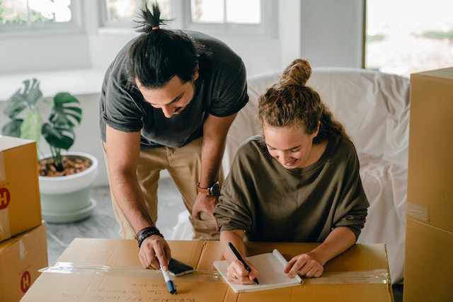Two tenants with their hair tied back review their end of tenancy cleaning checklist while preparing to move out